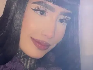 MarieBleuew poses close-up with long black hair and bangs, wearing a dark purple lace top while looking directly at the camera.