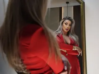 Glamorous blonde woman in a red dress posing confidently in a mirror for a stylish portrait.
