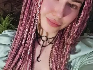 MarlanotDurden poses close-up with her long pink braided hair, wearing a light green top and a black choker with a silver charm.