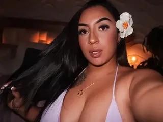 Beautiful woman with long dark hair and a white flower in a lavender bikini at a warm summer evening party.