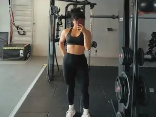 Fit woman in black gym wear taking a mirror selfie in a modern home gym setting.