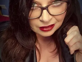 MatureBustyMilf looks into the camera with dark hair and red lipstick, wearing black glasses and a black top.