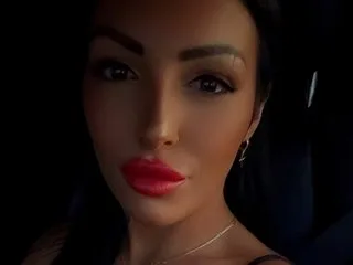 Meekyx — Meekyx looks directly into the camera with red lipstick and dark hair, a close-up shot of her face.