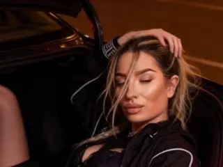 Glamorous woman in a black sporty outfit relaxing in a luxury convertible car at night.