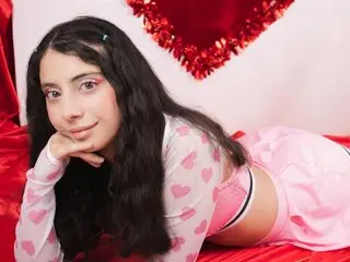 MegganParker has long dark hair and looks at the camera while resting her chin on her hand, wearing a pink polka-dot top.