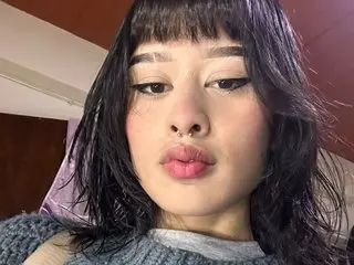 MeliStrawberry77 shows her face and dark hair with blunt bangs, looking directly at the camera in a close-up shot.
