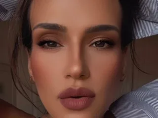 MiaNoir_X looks directly at the camera with a neutral expression, showing her face and dark hair.