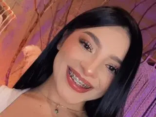 MiaWithhe smiles with her teeth showing, showing her long dark hair and light makeup in a close-up shot.
