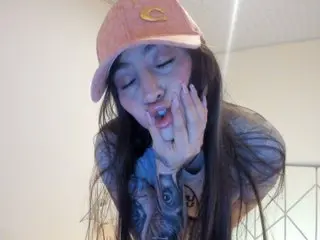 Mia_disnep licks her lips while looking down, showing her teeth and tongue with her long dark hair framing her face.