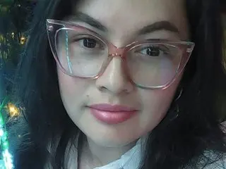 Miasantana18 wearing pink glasses and looking at the camera with a slight smile.