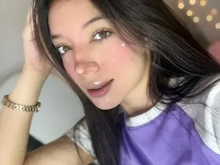 MichellDilucas poses with her hand near her face, showing her long dark hair and a close-up view of her face and neck.