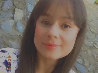 Mickekim looks at the camera with a soft smile, showing her long dark hair and face in a close-up shot.
