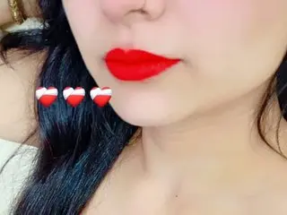 Midnight_Soniya looks into the camera with bright red lipstick and long dark hair.
