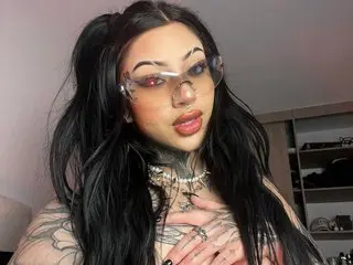 MilaMonty shows off her long dark hair and heavy tattoos while looking directly at the camera with a pouty expression.