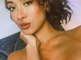 Close-up portrait of a woman with nose ring and gold earrings posing with a moody, aesthetic gaze.