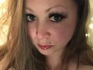 MissGoddessAmberRose looks into the camera with a close-up headshot, showing her long brown hair and eyes with heavy mascara.