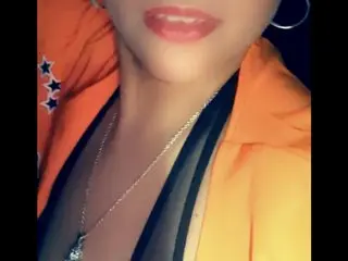 MixedBBWQueen shows her face and neck, wearing a bright orange top and a silver chain necklace.