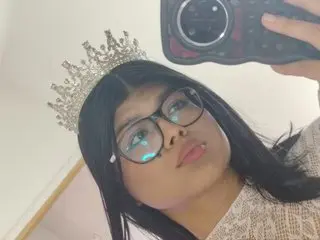 Myalopezz poses for a selfie wearing a silver tiara and glasses, showing her long dark hair and a light-colored patterned top.