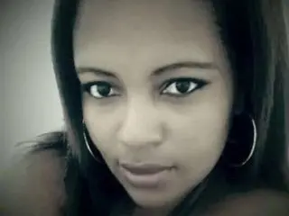 NIAA86 looks directly at the camera with a close-up headshot, showing her face and dark hair against a plain background.