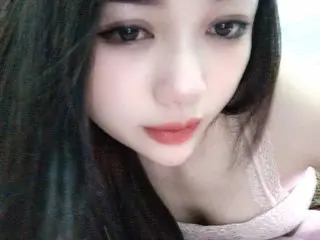Nana766 looks into the camera with long dark hair and red lipstick, wearing a pink lace top.