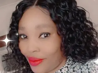 NastyXNice poses close-up with her long, wavy black hair and red lipstick, looking directly at the camera.