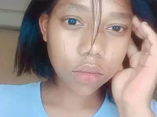 Nastynicolex19 looks into the camera with short dark hair and a light blue shirt, resting her hand against her face.