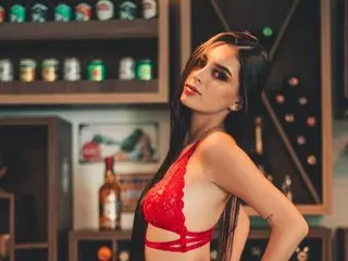 Beautiful woman in red lace lingerie posing in a moody, dimly lit bar setting.