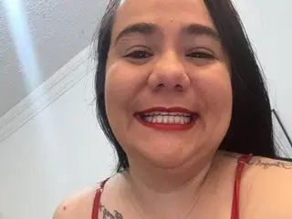 Nathalia_Chubby smiles for a close-up selfie, showing her dark hair and red lipstick while wearing a red strap top.
