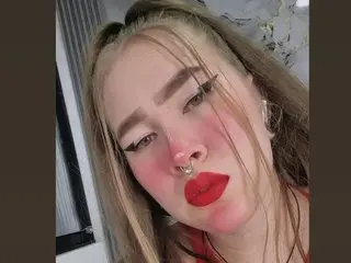 NathaxaLeans looks at the camera with a pouty expression, showing her blonde hair and red lipstick in a close-up shot.
