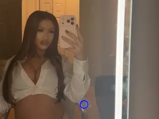Nativedreammxo poses in a white long-sleeve top, showing cleavage and her long dark hair in a mirror selfie.