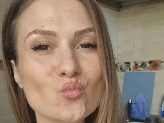 NattyReturn18 pouts her lips in a close-up selfie, showing her face and light brown hair against a soft indoor background.