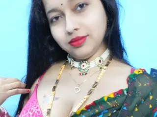 Neha_bhabhi poses with long black hair, wearing a white choker and a patterned blouse, showing cleavage and her bare shoulders.