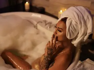 Relaxed woman with a white towel turban enjoying a relaxing bubble bath in a cozy, candlelit bathroom setting.