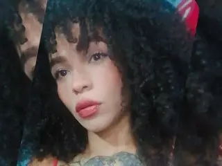 Nicoleinkk poses with her dark curly hair framing her face, showing her lips and eyes in a close-up shot.