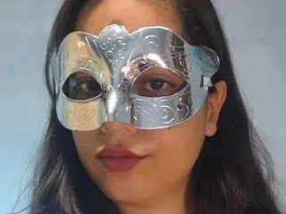 NinaCuteBunBun wears a shiny silver mask over her eyes, showing her long dark hair and face against a plain blue background.