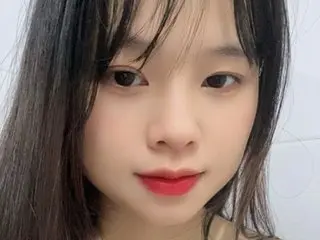 Ninakey looks at the camera with long dark hair and red lipstick, posing for a close-up headshot against a plain white background.