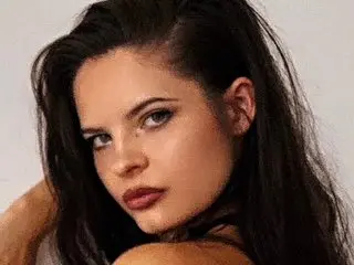 NixieNymph poses with her long dark hair framing her face, looking directly at the camera with a serious expression.