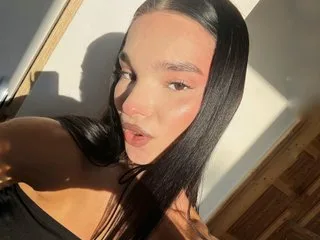 Noirbeauty looks into the camera with long dark hair and sunlit skin in a close-up shot.
