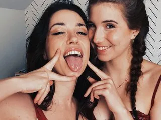 OdetteParker winks and sticks her tongue out while posing closely with a brunette friend against a patterned wall.