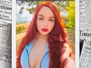 OhMySusan poses with long red hair, wearing a light blue bra that shows off her cleavage and cleavage area.