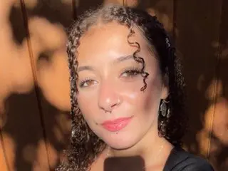 Opheliaheaven poses close-up, showing her face, curly hair, and a small nose piercing while looking directly at the camera.