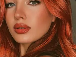 OvaParlow poses with a close-up view of her face, showing her red hair and orange-red lipstick.