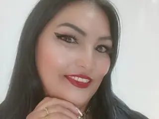 Smiling woman with long black hair and bold red lipstick posing against a white background.