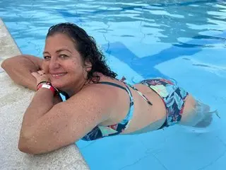 Smiling woman in a floral bikini relaxing in a bright blue swimming pool on a sunny summer day.