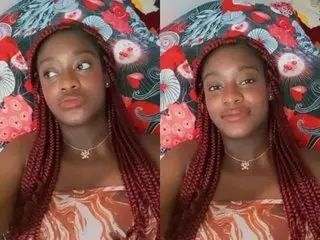 Young woman with long red braids wearing a patterned tube top relaxing against floral pillows.