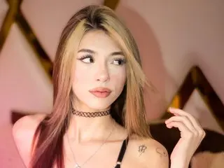 ParisSpring looks off to the side with long blonde and brown hair, wearing a black choker and a thin necklace.