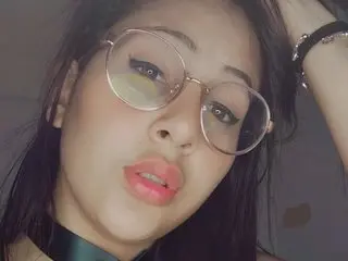 Parisannee poses with a pouty expression, showing her long dark hair and wearing round glasses in a close-up shot.