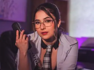 Pauliinamayerss poses with her hands near her face, wearing a white button-down shirt and glasses with her dark hair pulled back.