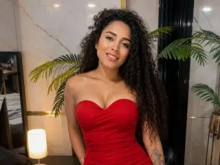 PaulinaRizzo smiling in a red strapless dress with her long curly hair down.