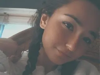 PlayfulPixieFox smiles while looking directly at the camera with her dark hair styled in long braids.